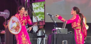 En la imagen se puede ver a Ana Bárbara con una vestimenta de charro en color rosa fiusha y con la cara enojada al intentar cantar con su micrófono descompuesto