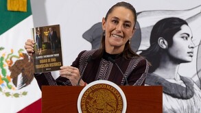 Claudia Sheinbaum mostrando su nuevo libro en conferencia matutina.