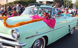 Persona con máscara de Blue Demon en un carro clásico color turquesa