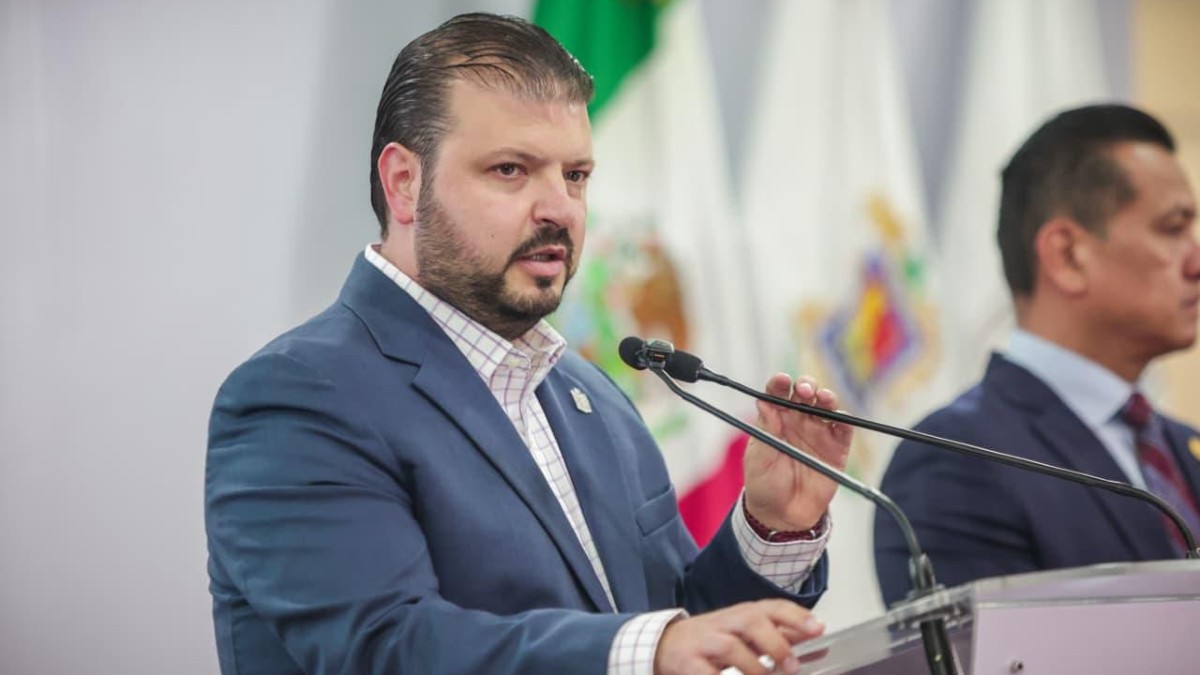 Secretario de Gobierno de Michoacán, Raúl Zepeda Villaseñor durante conferencia de prensa con bandera de México de fondo