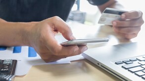 Joven sosteniendo un teléfono celular y una tarjeta bancaria porque no puede realizar transferencias de SPEI.