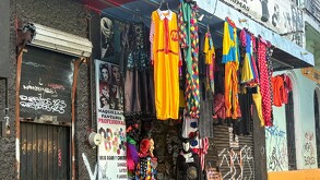 Fachada de una tienda de disfraces en un edificio antiguo. Ropa de Halloween y Carnaval cuelga en ganchos: disfraces de payaso, vestido amarillo y prendas
