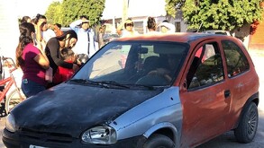 En la imagen se ve un carro con cofre negro y rojo rodeado de personas entre ellos niños, tras accidente en San Perdo.