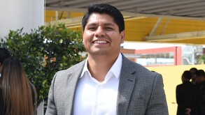 Hombre con traje sonriendo a la cámara.