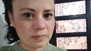 Mujer vestida con sudadera verde y cadena viendo hacia la cámara.