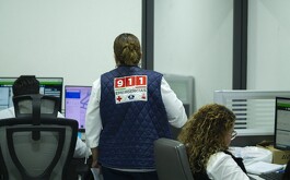 Mujer de espaldas con chaleco del C5 y llamado de emergencias 911