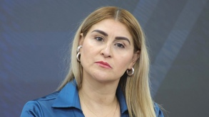 Mujer rubia con una blusa en color azul mirando fijamente hacia un punto.