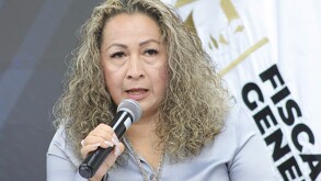 Mujer de la tercera edad con cabello rubio hablando con un micrófono en la mano.