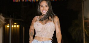 Karina Torres aparece vestida con un pantalón de mezclilla y un top color beige, al fondo se puede ver un decorado de colores rojo, amarillo y azul. Karina Torres aparece vestida con un pantalón de mezclilla y un top color beige, al fondo se puede ver un decorado de colores rojo, amarillo y azul.