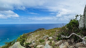 Isla Lizard en Australia, vista desde un acantilado, al fondo se aprecia un par de barcos, y nubes en el cielo.