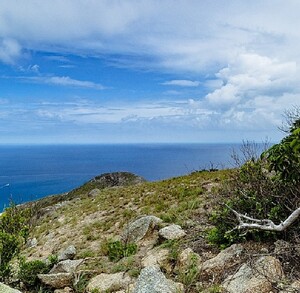 Isla Lizard en Australia, vista desde un acantilado, al fondo se aprecia un par de barcos, y nubes en el cielo.