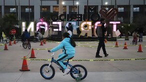 Niña vestida de azul cielo en la Plaza Mayor de Torreón paseando en su bicicleta.