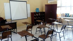 En la imagen se ve un salón de clases sin alumnos.