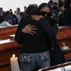 Mujeres vestidas de negro abrazándose frente a un féretro, durante un funeral.