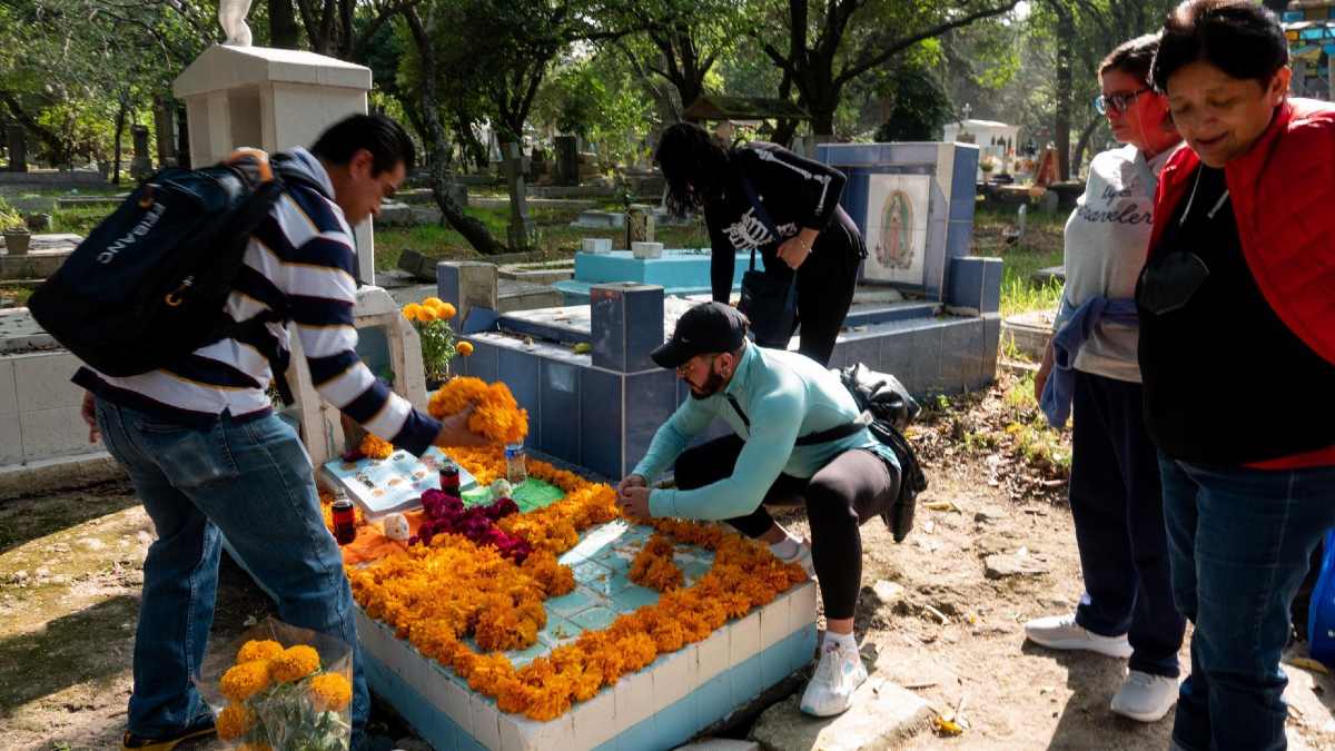 Familias adornando las tumbas de sus seres queridos en Día de Muertos Familias adornando las tumbas de sus seres queridos en Día de Muertos