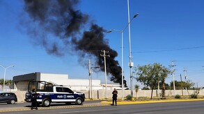 Humo negro saliendo de instalaciones de Aeropuerto de Torreón junto a una patrulla de policía de Torreón