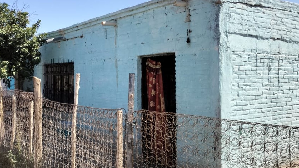 Casa de adobe en color azul menta y una cerca de residuos de colchones Casa de adobe en color azul menta y una cerca de residuos de colchones