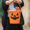 Niño usando disfraz y sosteniendo una calabaza de Halloween llena de dulces tras pedir dulce o truco Niño usando disfraz y sosteniendo una calabaza de Halloween llena de dulces tras pedir dulce o truco