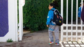Niño con uniforme azul en la entrada de una escuela ubicada en Puebla.
