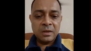 Hombre llorando frente a una cámara con una camisa tipo polo color azul con mostaza.