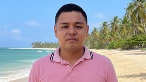 Hombre joven con playera rosa en una playa de Veracruz.