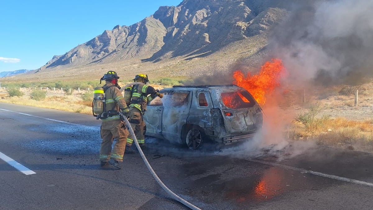 Bomberos intentando sofocar el incendio de un carro.