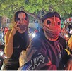 Primer plano de una pareja en motocicleta durante una rodada nocturna. Ambos usan máscaras de terror con ojos de costura. Están rodeados por otros motociclistas Primer plano de una pareja en motocicleta durante una rodada nocturna. Ambos usan máscaras de terror con ojos de costura. Están rodeados por otros motociclistas