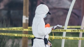 Persona con cubrebocas y una bata que le cubre todo el cuerpo caminando en una escena del crimen.