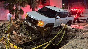 Camioneta blanca con las luces prendidas, al borde de un pozo en Torreón