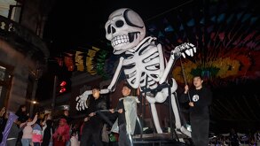 unos jóvenes empujan una figura de esqueleto en el desfile de día de muertos en puebla