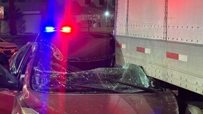 Carro rojo destruído al impactarse en la parte trasera de un tráiler estacionado