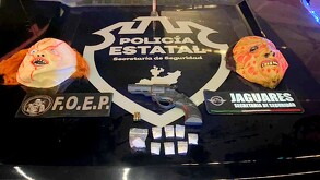 Pistola junto a balas, sobres de presunta droga y máscaras de Halloween sobre el cofre de una patrulla de la Policía Estatal de Jalisco