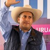 Carlos Manzo, alcalde de Uruapan, Michoacán, levantando la mano y usando un sombrero, camisa y chaleco azul, durante presentación pública