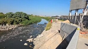 Canal de aguas residuales a un costado del Aeropuerto de Guadalajara. Miembros de Protección Civil y Bomberos de El Salto en la orilla y árboles a la izquierda