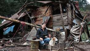 una mujer acompañada de su perro frente a su casa dañada por las lluvias en la sierra norte de puebla