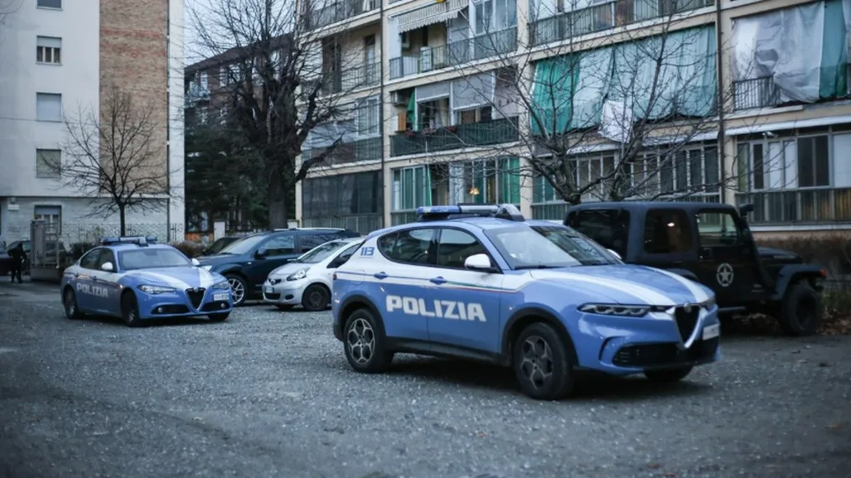 Patrullas de Policía de Italia en un estacionamiento frente a edificios y árboles secos