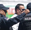 Dos hombres vestidos con uniforme policial vistos de espaldas.