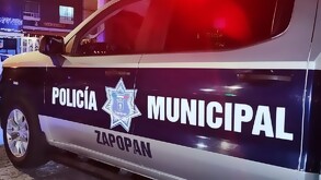 Vista lateral de una patrulla de la Policía Municipal de Zapopan estacionada en la calle de noche y con la sirena encendida