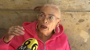 Mujer de la tercera edad con cabello rubio y lentes hablando al micrófono de canal 6