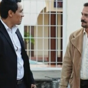 dos hombres platicando, uno vestido con una chamarra café y el otro de negro