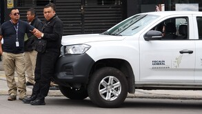 Hombre vestido de negro recargado sobre un auto blanco con las siglas de la Fiscalía de Puebla.