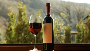 Copa de vino junto a una botella. Naturaleza como fondo.