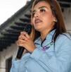 Grecia Quiroz tomando un micrófono