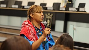 Alma López, mujer wixárika en el Centro Integral de Servicios Zapopan sosteniendo un micrófono con personas alrededor.