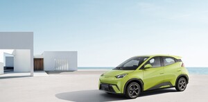 Un coche eléctrico BYD Seagull de color verde lima o amarillo brillante está estacionado en una plataforma de concreto junto a una estructura blanca minimalista