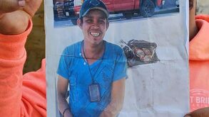 Martín Jaramillo aparece con una camisa azul y gorra , además trae colgando una credencial.