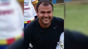 Abogado ejidal Essaú Román Pérez viendo de frente y vistiendo playera negra con logo de nike en un campo deportivo y con un trofeo a un lado