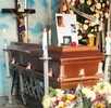 Cajón fúnebre con veladras en las cuatro esquinas y arreglos florales