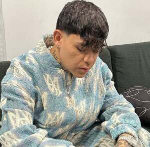 Junior H con la mirada hacia abajo sentado en un sillón