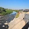 Canal de aguas residuales a un costado del Aeropuerto de Guadalajara. Miembros de Protección Civil y Bomberos de El Salto en la orilla y árboles a la izquierda
